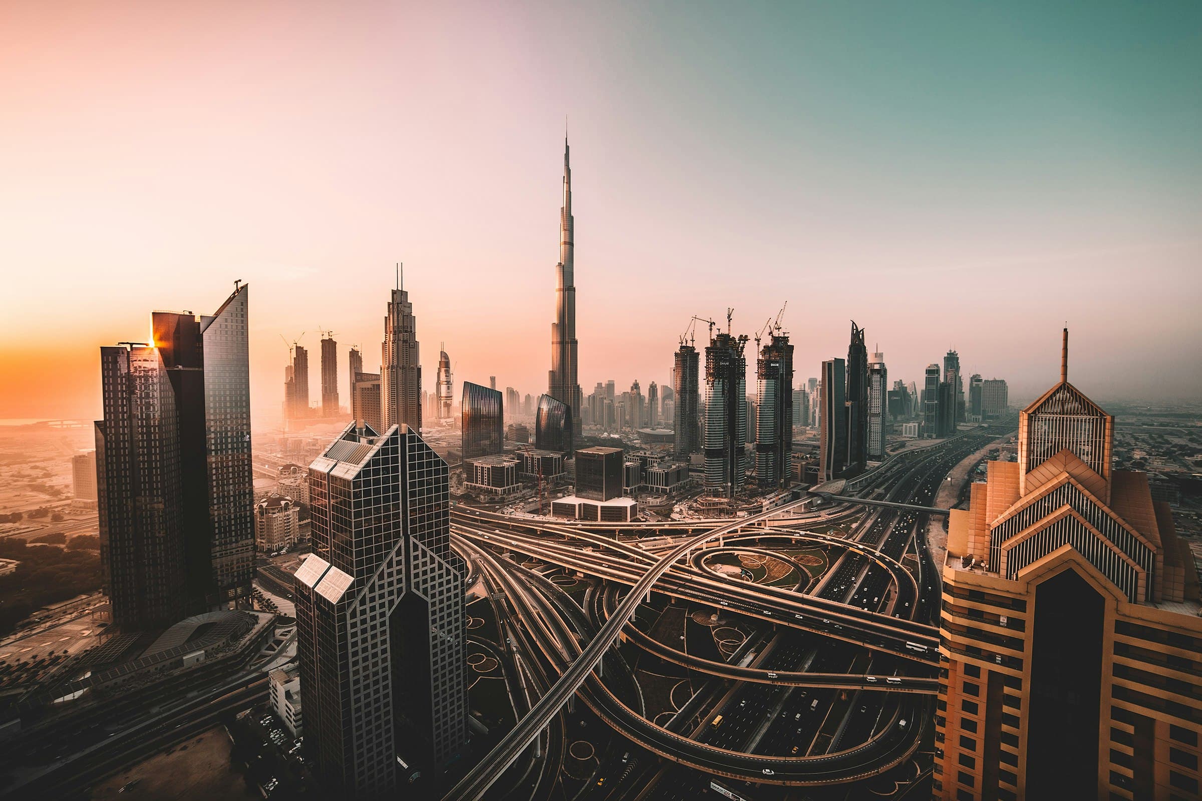 Dubai skyline at sunrise with Burj Khalifa rising above the interchange